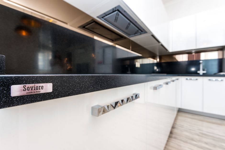 Modern kitchen with white cabinets and a sink under a stone countertop.